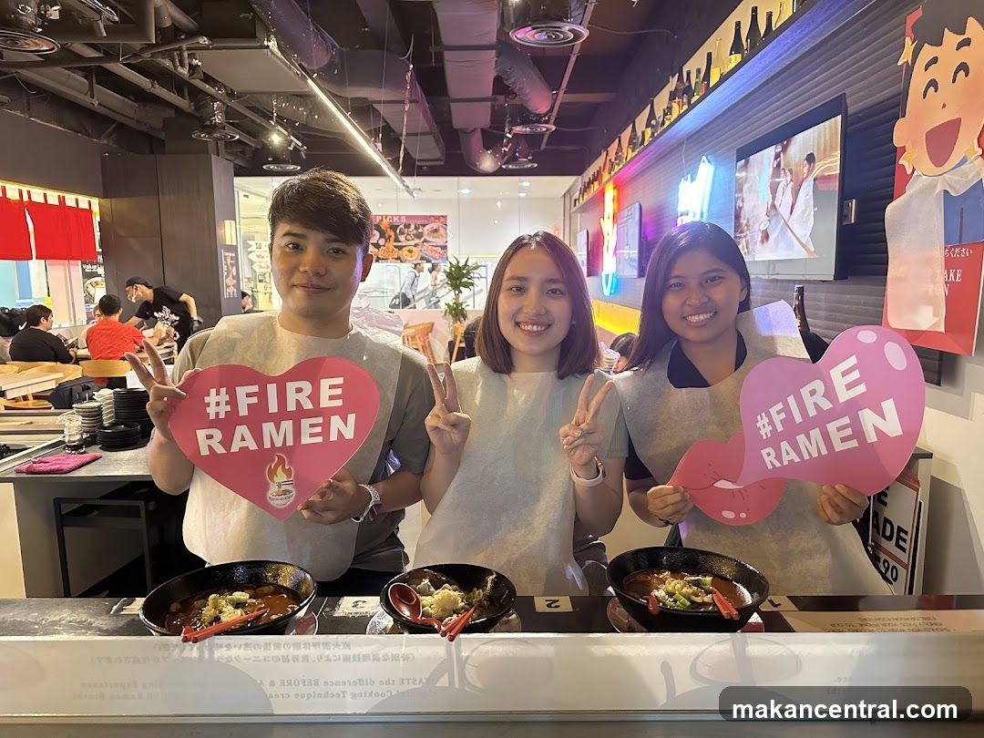 Staff holding promotional signs at ramen counter