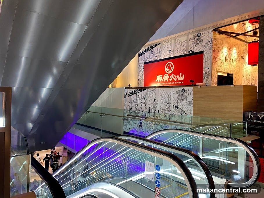 Interior of shopping mall with escalators and restaurant signage