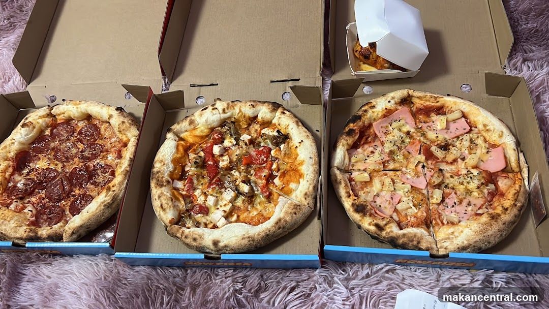 Three pizzas in boxes on a fluffy surface