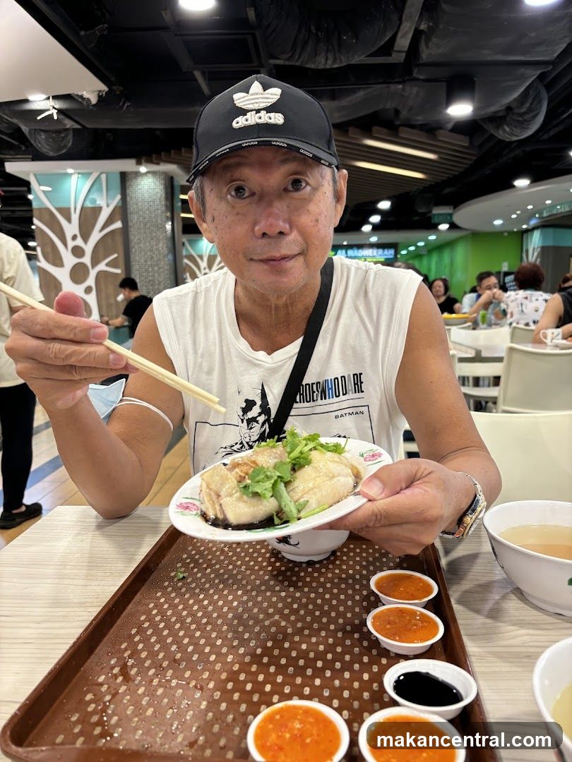 Man eating Hainanese chicken rice in food court
