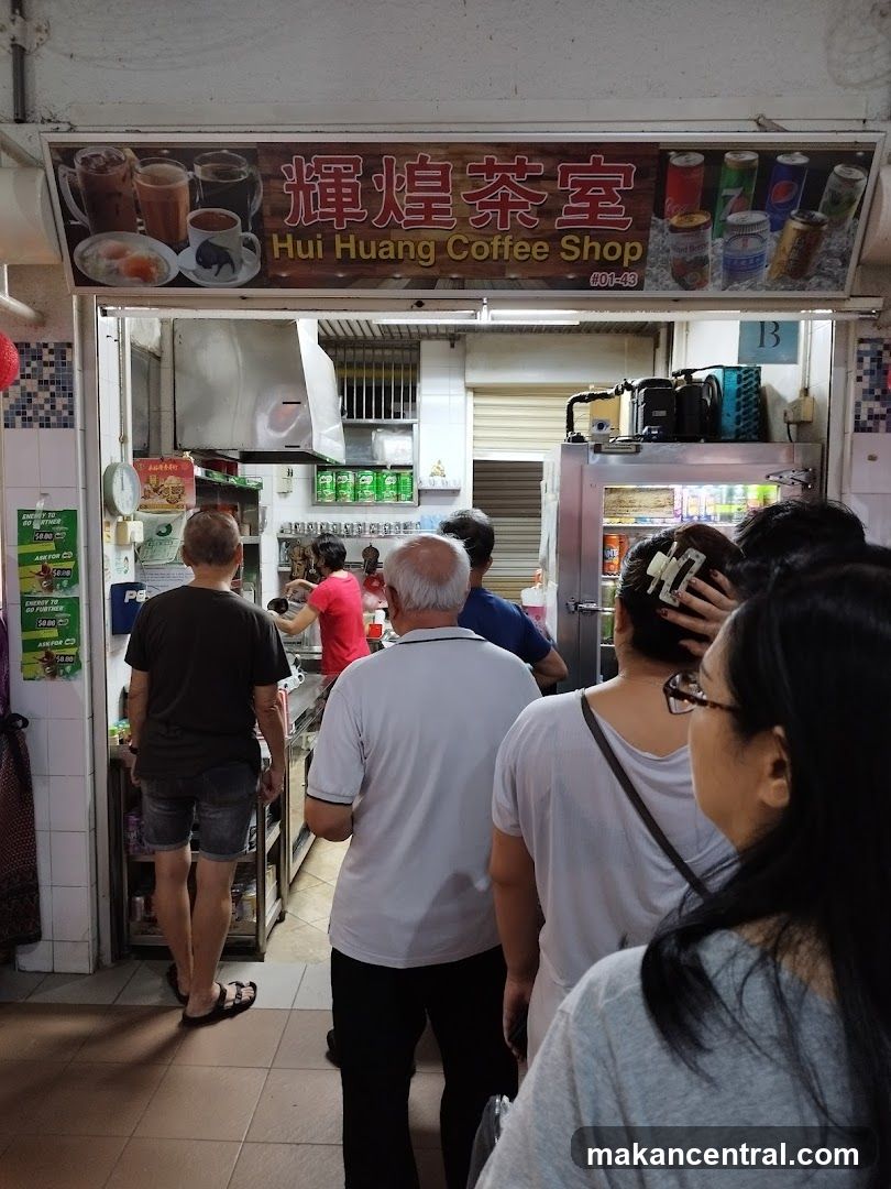 Exterior view of a coffee shop entrance with signage displaying "輝煌茶室" and "Hui Huang Coffee Shop #01-48" above the doorway. Customers are seen inside and outside the shop, some waiting in line. The interior shows a counter area, refrigerated display units, and shelves stocked with canned drinks. A staff member in red is preparing food or drink behind the counter.