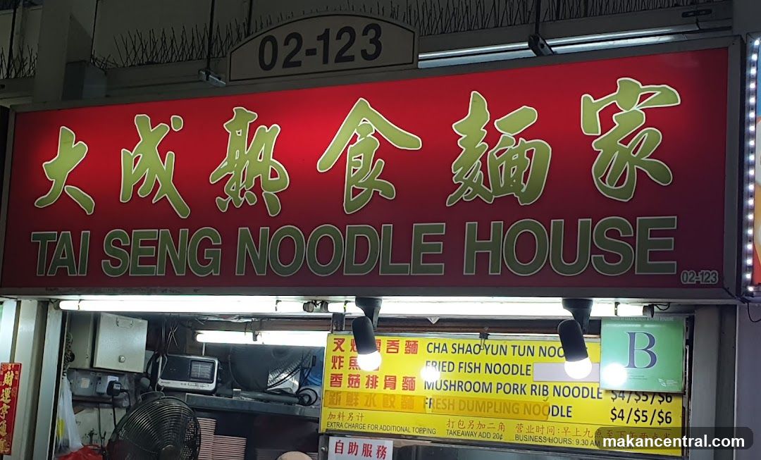 Red sign with green Chinese characters '大成熟食麵家' above English name 'TAI SENG NOODLE HOUSE'. Signage includes unit number 02-123. Below, a yellow menu board lists items like 'Fried Fish Noodle', 'Mushroom Pork Rib Noodle', and 'Fresh Dumpling Noodle' with prices $4/$5/$6. A green 'B' sign is visible to the right.