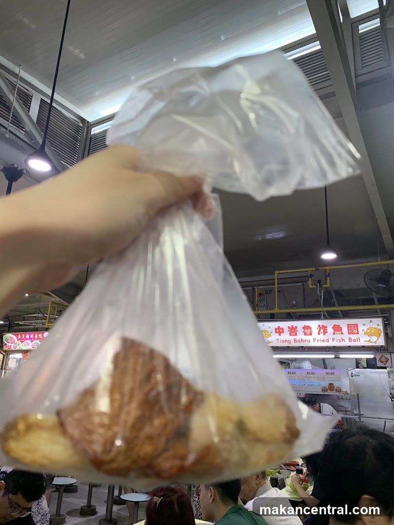 Hand holding food in plastic bag at hawker center