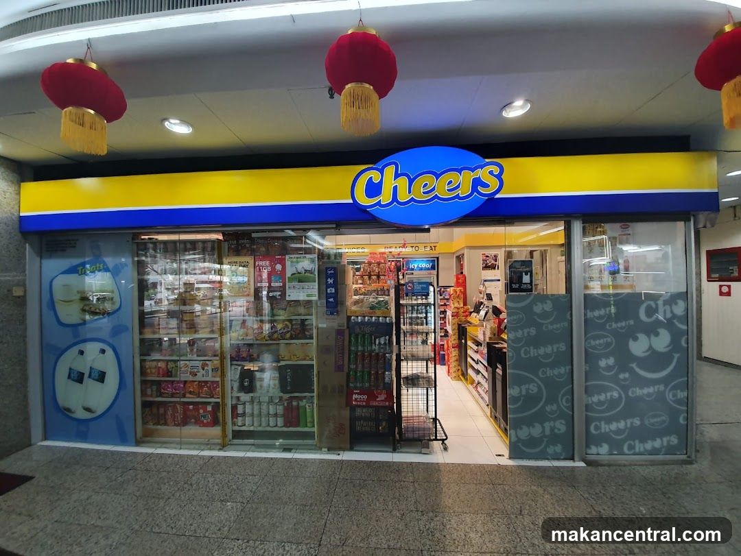 Storefront with blue and yellow signage featuring the word 'Cheers' in stylized font. Red lanterns hang from ceiling above entrance. Glass doors display product shelves inside, including beverages and snacks. Interior lighting illuminates aisles. Side panels have repeating 'Cheers' logo design. No menu or printed materials are visible on the storefront itself.