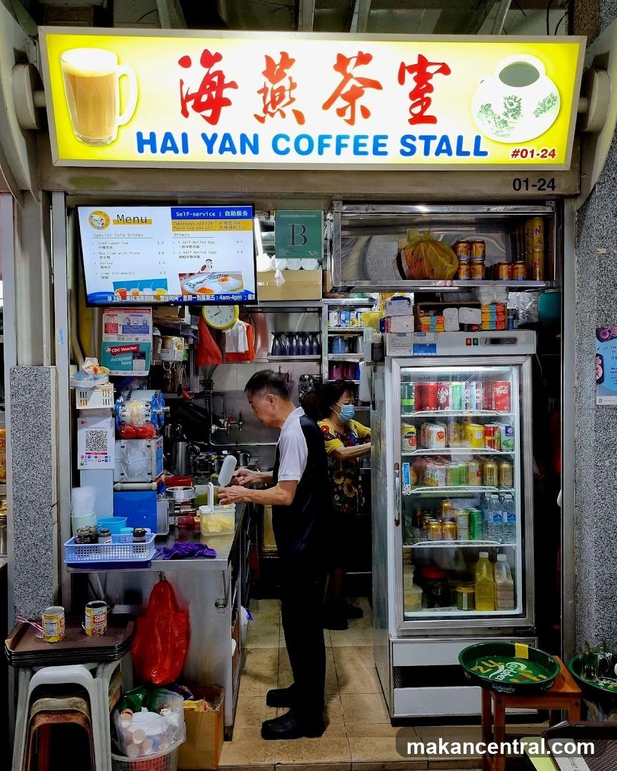Exterior storefront of a coffee stall with bright yellow signboard displaying "海燕茶室" and "HAI YAN COFFEE STALL #01-24". The shop has an open kitchen area, a refrigerator stocked with beverages, and staff working inside. A digital menu board is mounted above the counter.