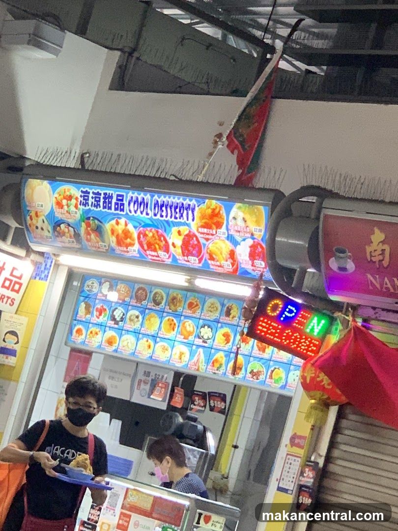 A storefront with a bright blue LED sign displaying '涼涼甜品 COOL DESSERTS' above the entrance. A red neon 'OPEN' sign is mounted to the right of the shop door. Two people wearing face masks are visible inside, one holding a tray. The ceiling has exposed pipes and a red flag hanging from it. A partially visible red banner with Chinese characters hangs on the right side.