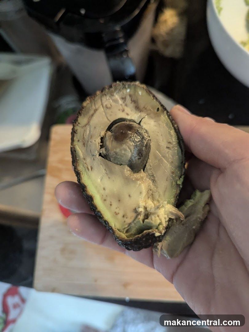 Hand Holding Halved Avocado