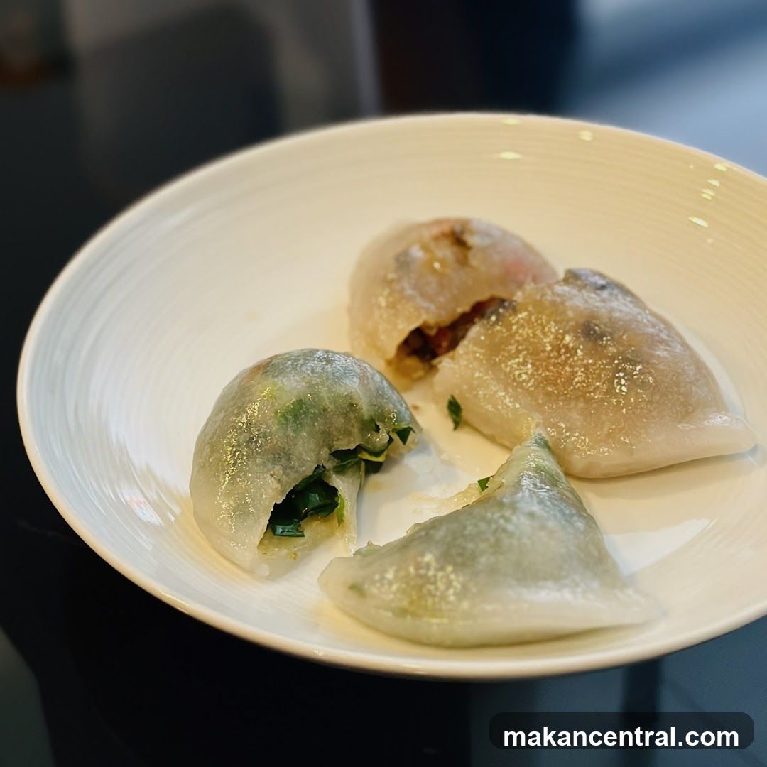 Three translucent dumplings with green filling are served on a white plate with concentric ridges. The dumplings appear partially eaten or cut open, revealing their fillings. The background is dark and out of focus.