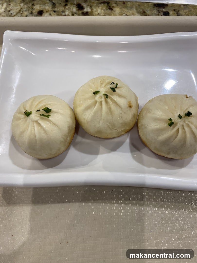 Three steamed buns on a white plate