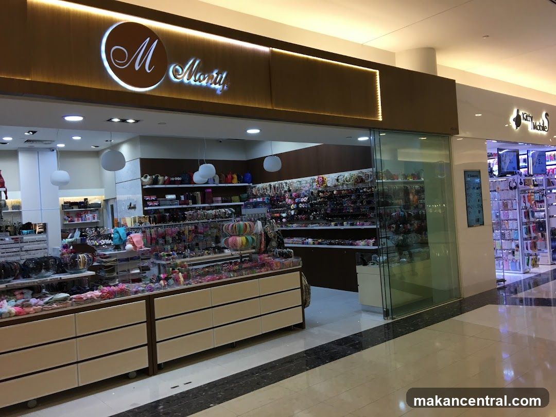 Storefront with illuminated 'M Montif' logo on a brown panel above glass entrance. Interior displays colorful accessories, shelves, and display counters. Adjacent store sign reads 'Kitty Mobile'.