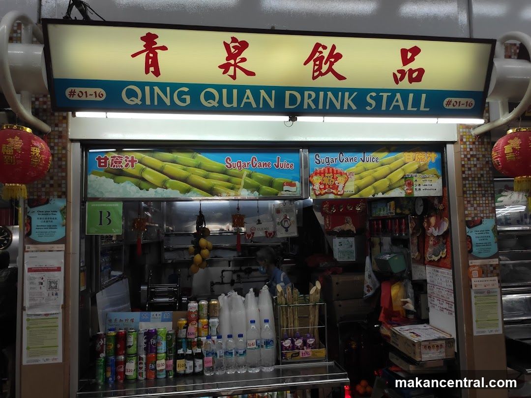 A brightly lit storefront with a prominent sign reading '青泉飲品' and 'QING QUAN DRINK STALL #01-16'. The shop features large posters advertising sugar cane juice, with images of sugarcane stalks. Inside, a staff member is partially visible behind the counter. The front displays bottled water, canned drinks, and bamboo sticks. Red lanterns hang on either side. The interior appears busy with equipment and supplies.
