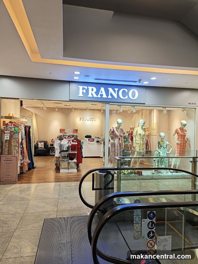 Storefront with illuminated "FRANCO" sign above glass entrance. Inside, mannequins display dresses; racks of clothing are visible on left. Escalator leads to level 2. No menus or printed materials visible.
