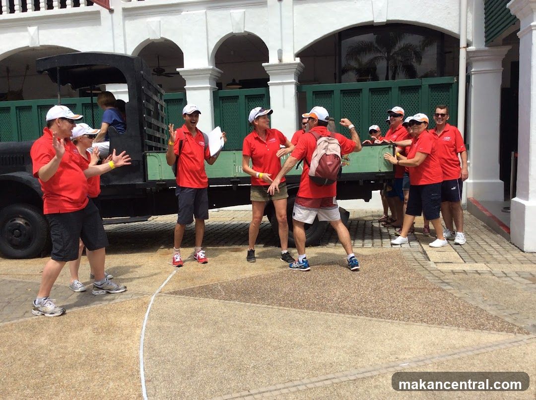 Group of people in red shirts posing near vintage vehicle