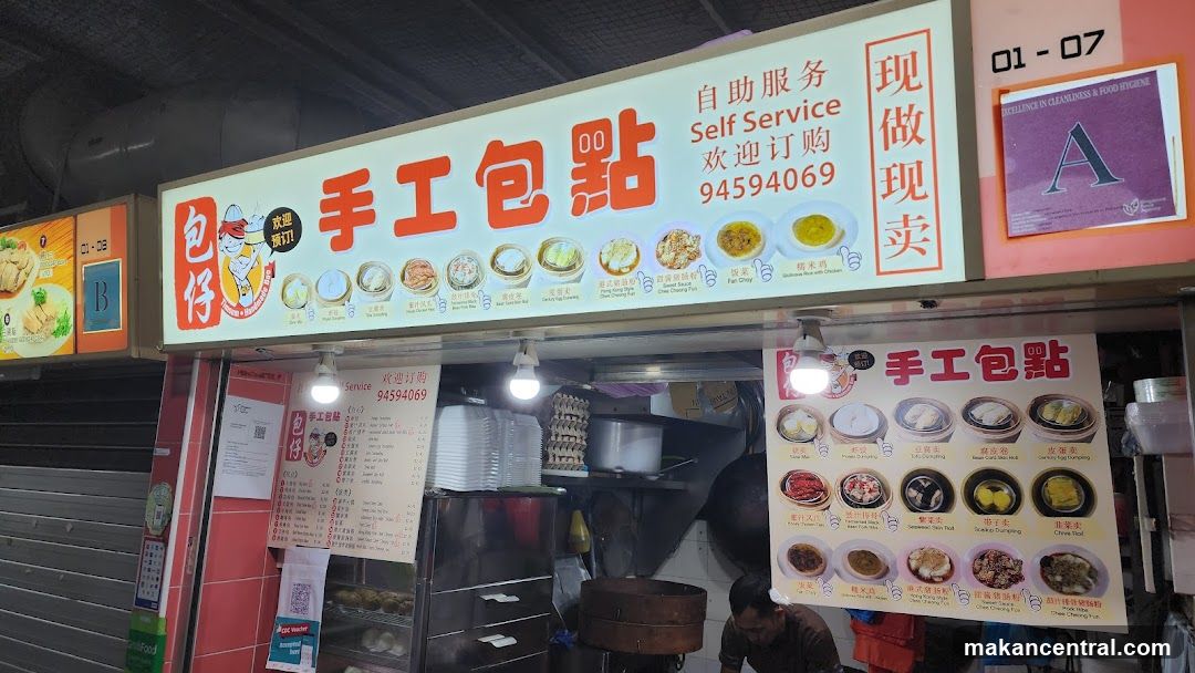 Exterior storefront of a dim sum stall with bright signage in Chinese characters and English. Sign includes 'Self Service', phone number 94594069, and '现做现卖' (Made to order). Visible interior elements include steamers, stacked bowls, and a worker preparing food. Adjacent shop signs are partially visible.