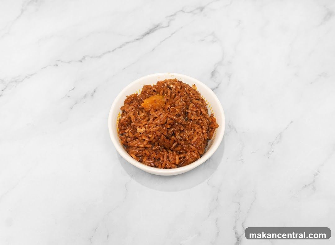 A small white bowl containing brown rice with a piece of orange-colored ingredient, placed on a white marble surface with gray veining.