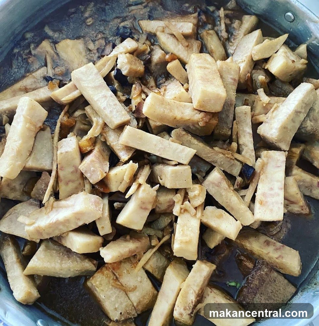 A close-up view of chopped vegetables in a dark sauce inside a metal pot or pan.