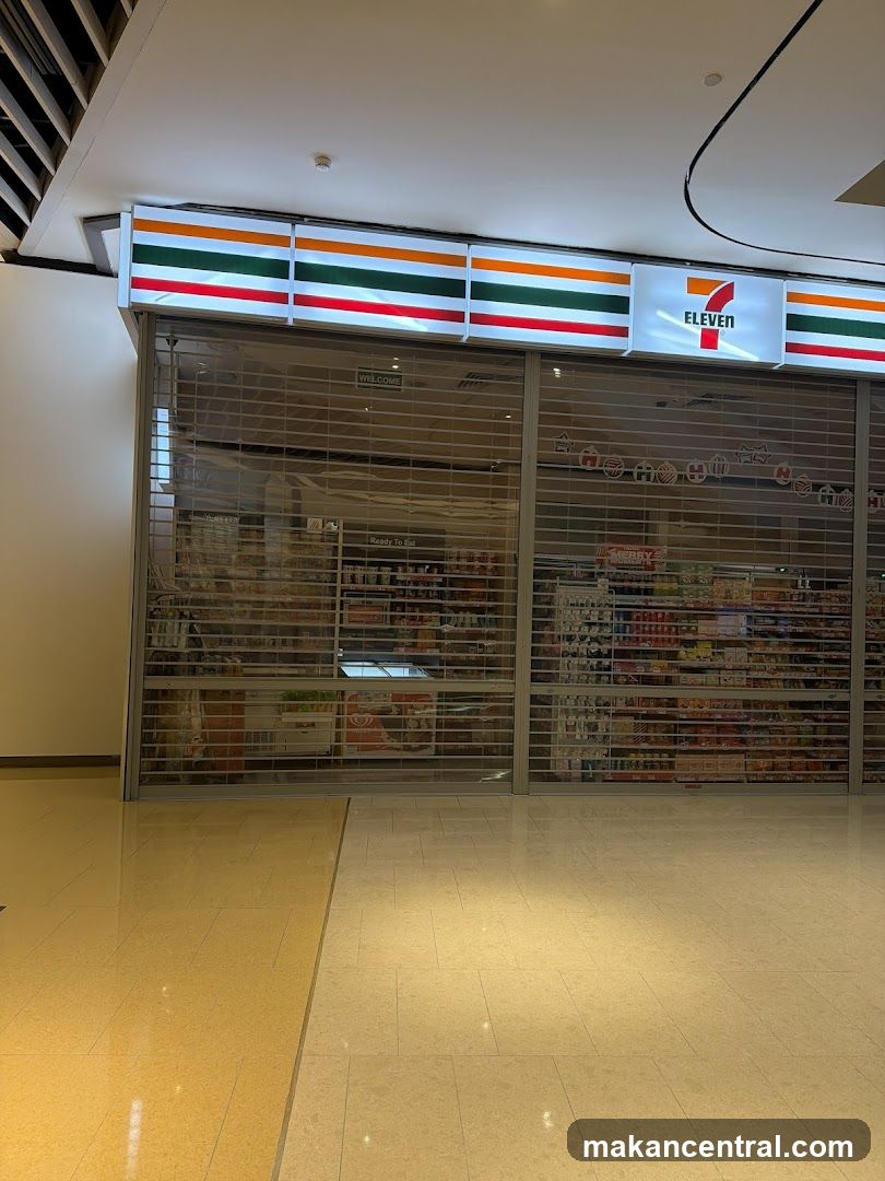 Storefront with metal security gates down, illuminated 7-Eleven logo and striped signage above entrance. Interior shelves stocked with products are visible through the gates. Clean, tiled floor in foreground.