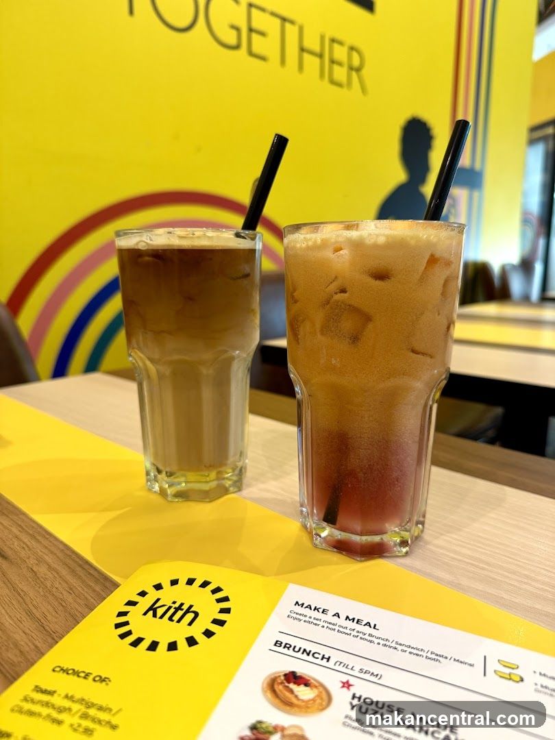 Two iced drinks on a table with a menu