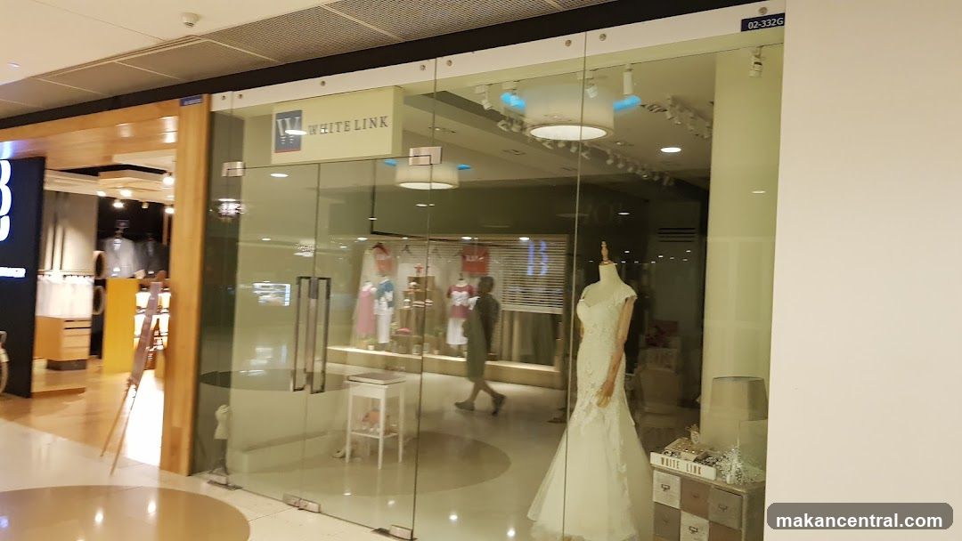 A glass storefront with the "WHITE LINK" logo visible above the entrance. Inside, mannequins display dresses, and clothing racks are visible. A person walks through the store.
