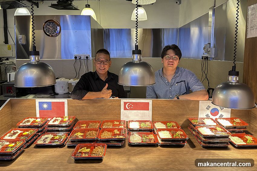 Two Men Behind a Counter with Bento Boxes