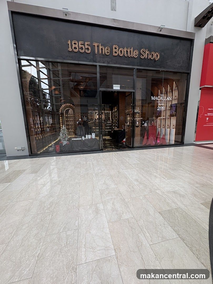 The exterior of a bottle shop with the name "1855 The Bottle Shop" displayed prominently above the entrance. The shop has large glass windows showcasing various bottles and displays inside. One display features "The Macallan Time Space Mastery" with bottles and branding.